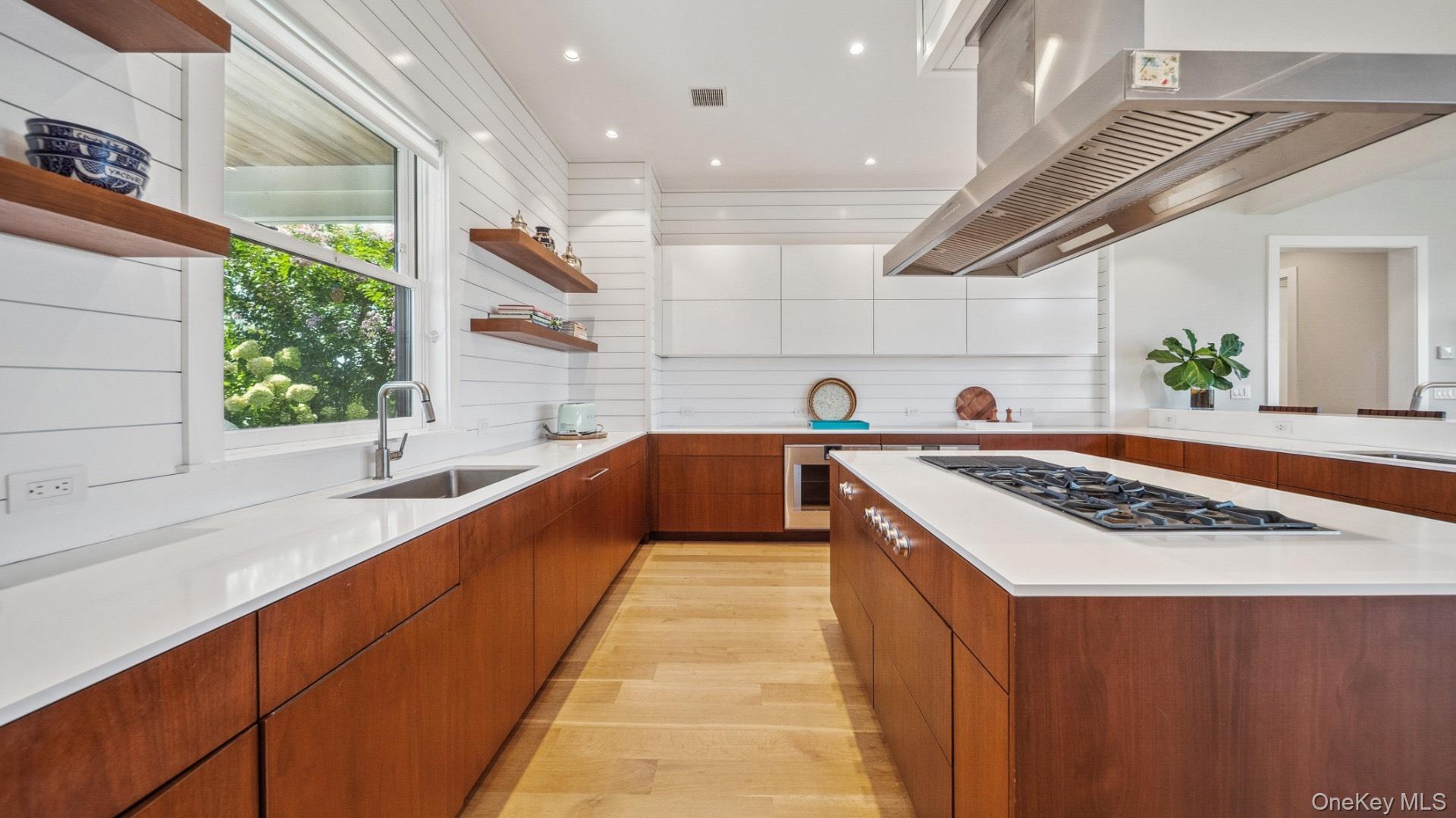 102-92 Dune Road Westhampton Beach, NY 11978 - Photo 10 of 40 Kitchen featuring open shelves, brown cabinetry, light wood finished floors, modern cabinets, and extractor fan