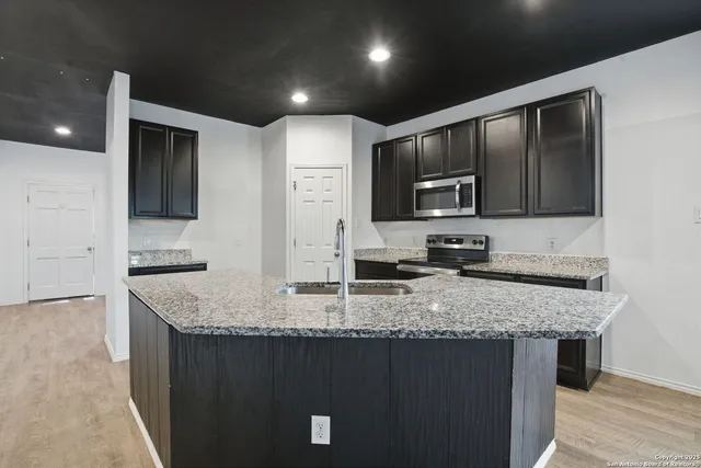 a kitchen with granite countertop stainless steel appliances a sink stove top oven and granite counter tops