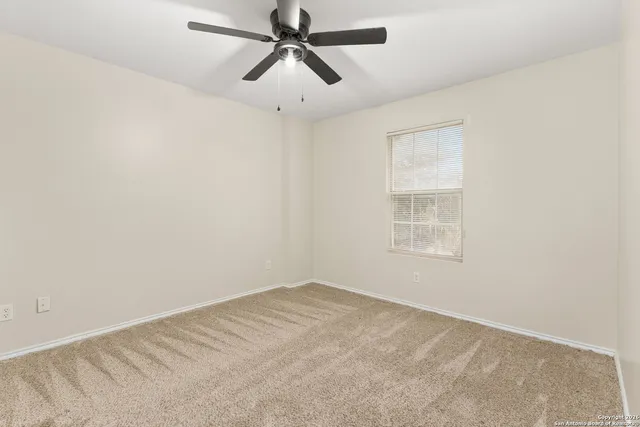 an empty room with a window and a fan