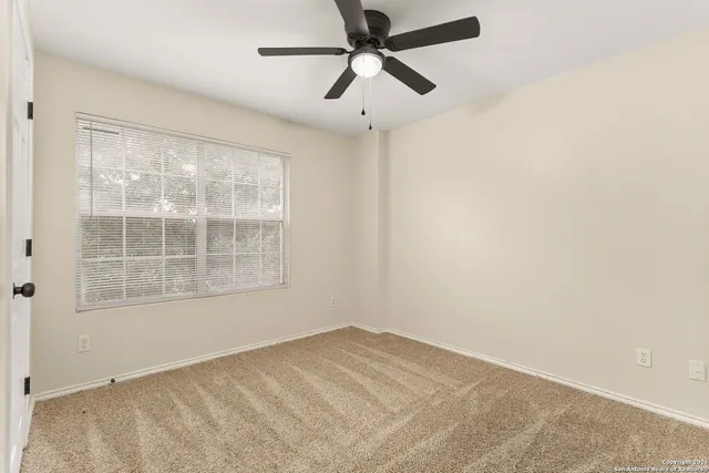 an empty room with a window and a ceiling fan