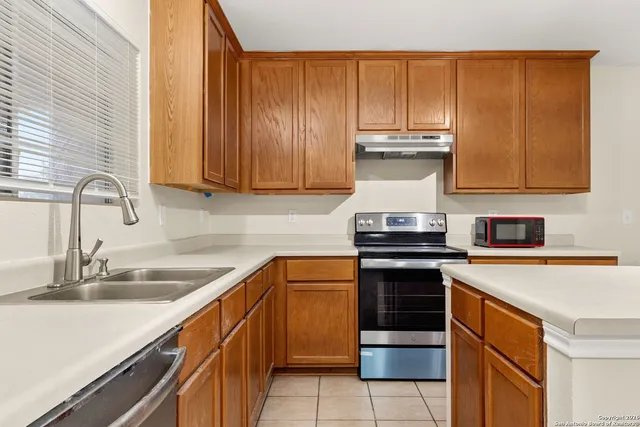 a kitchen with stainless steel appliances granite countertop wooden cabinets and a stove top oven