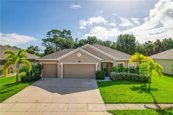 a front view of a house with a yard and potted plants