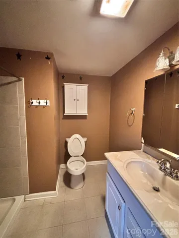 a bathroom with a granite countertop sink toilet and mirror
