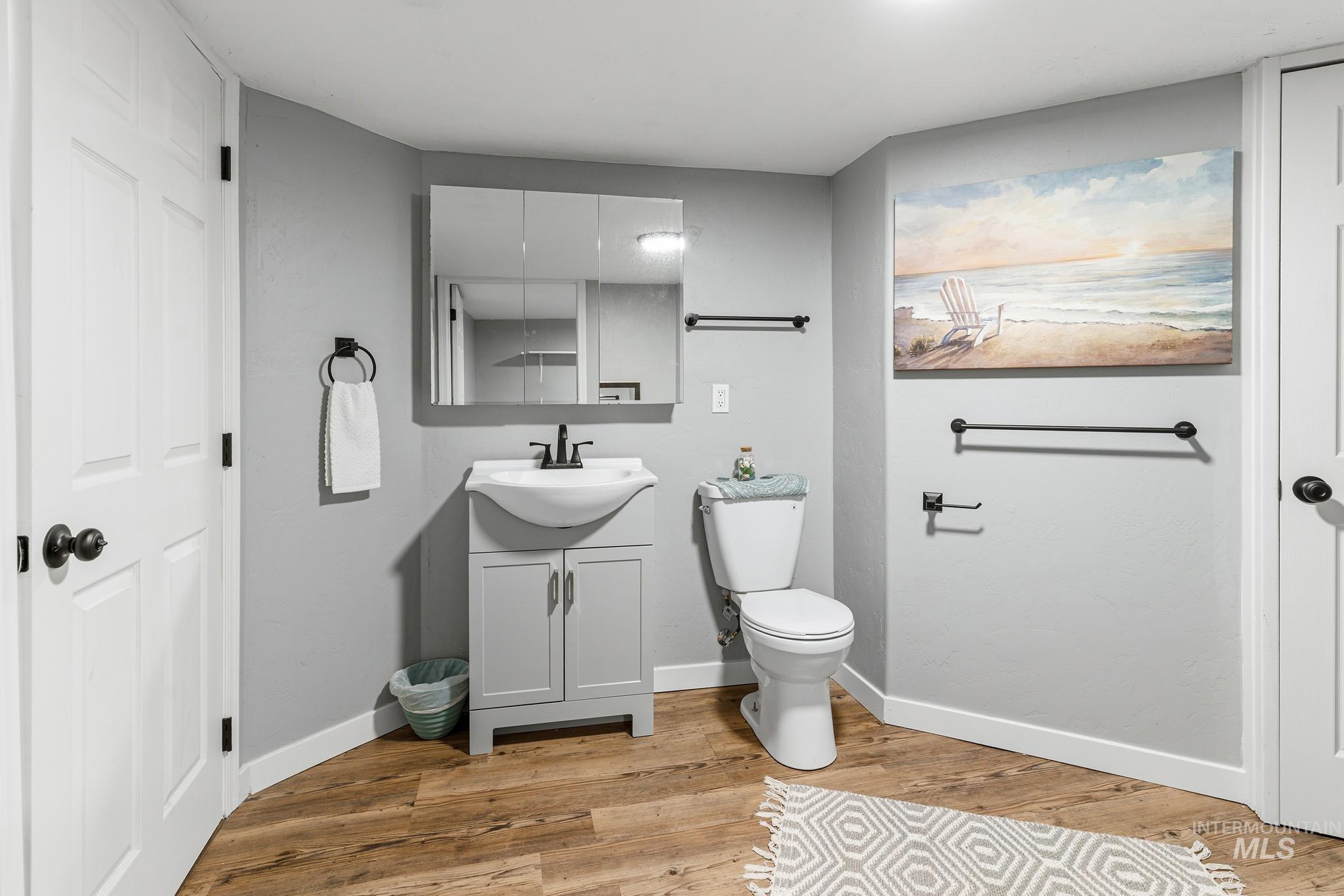 619 Thain Road Lewiston, ID 83501 - Photo 9 of 44 Bathroom featuring a pedestal sink vanity with cabinet storage, wood-finish flooring, and matte black fixtures