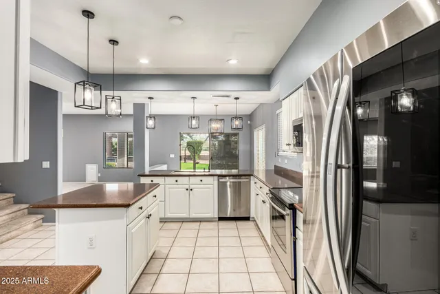 a large kitchen with granite countertop a sink and white cabinets
