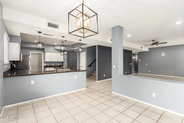 a view of an empty room and chandelier fan