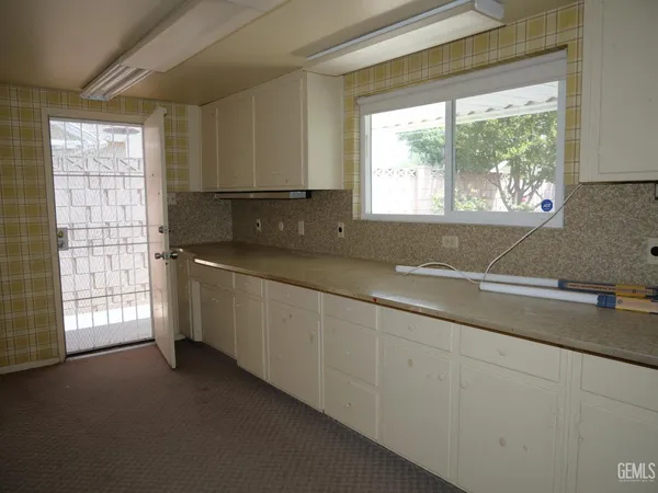 a kitchen with granite countertop a sink window and cabinets