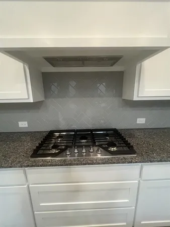 a close view of stove a microwave oven with white cabinets