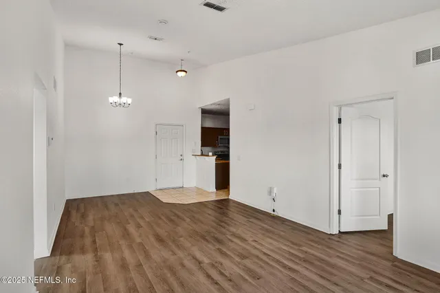 a view of an empty room with wooden floor and windows