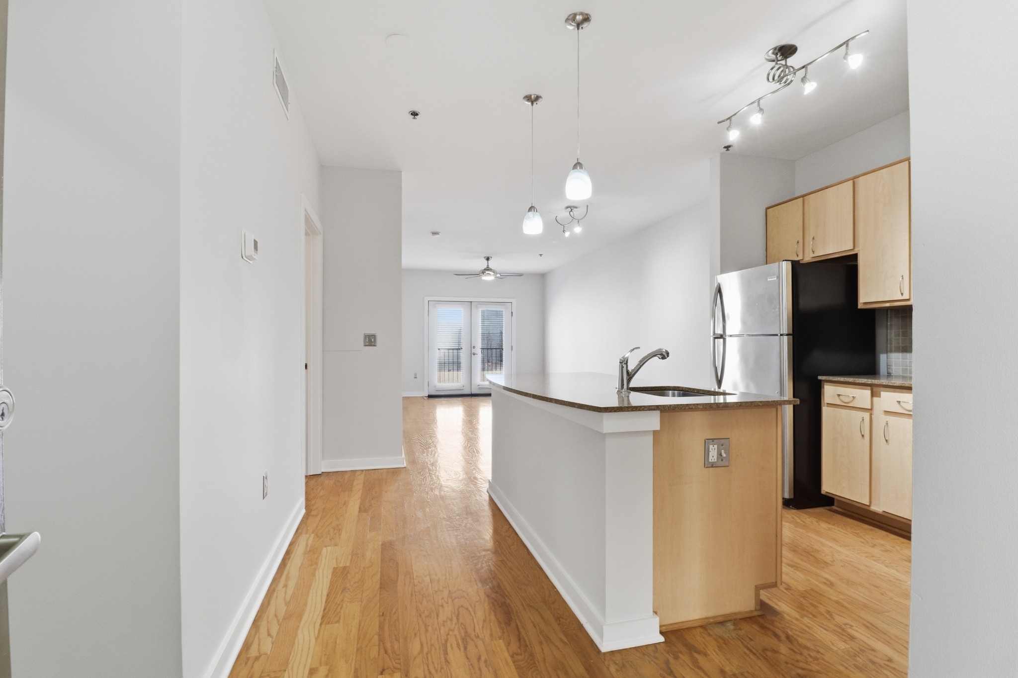 a view of a kitchen with kitchen island a sink wooden floor and a refrigerator