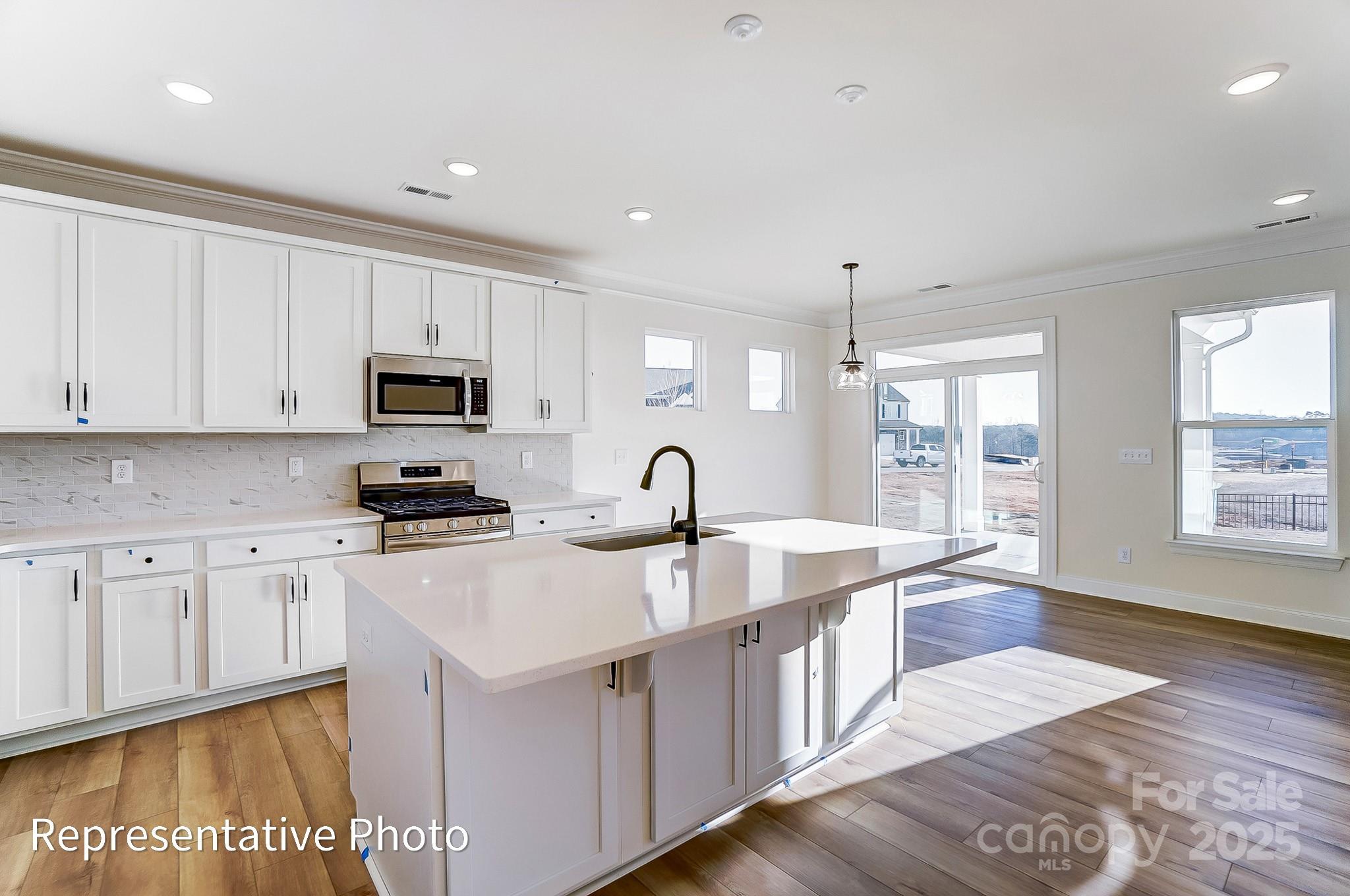 5009 Raging Crk Drive Indian Trail, NC 28079 - Photo 7 of 28 a large white kitchen with stainless steel appliances granite countertop a stove a sink dishwasher and white cabinets with wooden floor