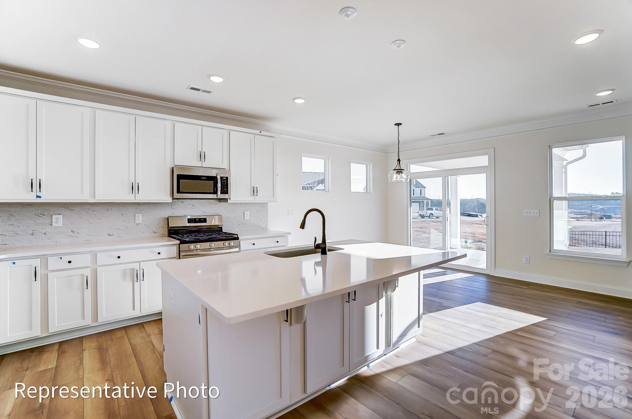 5009 Raging Crk Drive Indian Trail, NC 28079 - Photo 7 of 39 a large white kitchen with stainless steel appliances granite countertop a stove a sink dishwasher and white cabinets with wooden floor