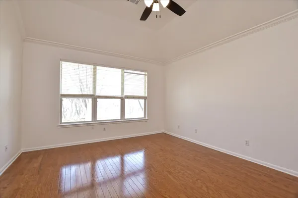 an empty room with ceiling fan and window