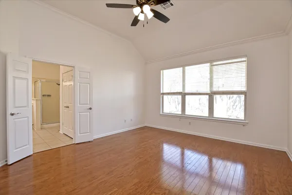 an empty room with wooden floor chandelier and windows