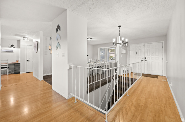 9750 Indian Ridge Drive Sandy, UT 84092 - Photo 13 of 40 Hallway with light wood finished floors, hanging lights, and a textured ceiling