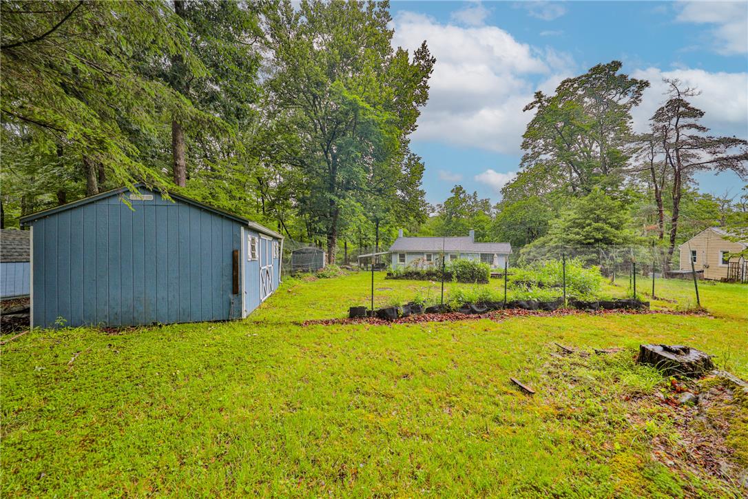 5599 Minks Pond Road Bushkill, PA 18324 - Photo 57 of 64 A spacious yard with verdant grass, mature trees, and a practical storage shed.