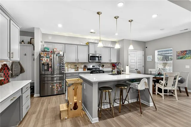 a kitchen with stainless steel appliances kitchen island granite countertop a table chairs refrigerator and sink