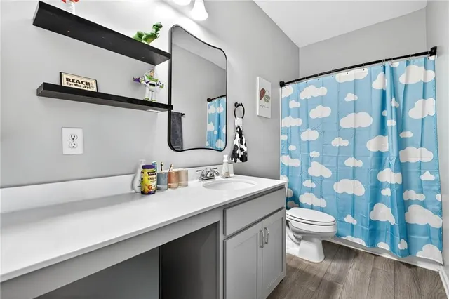 a bathroom with a granite countertop sink a toilet and a mirror