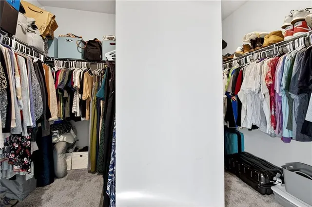 a view of walk in closet with clothes and shoes