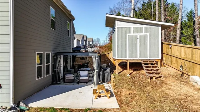 a backyard of a house with wooden fence and large trees