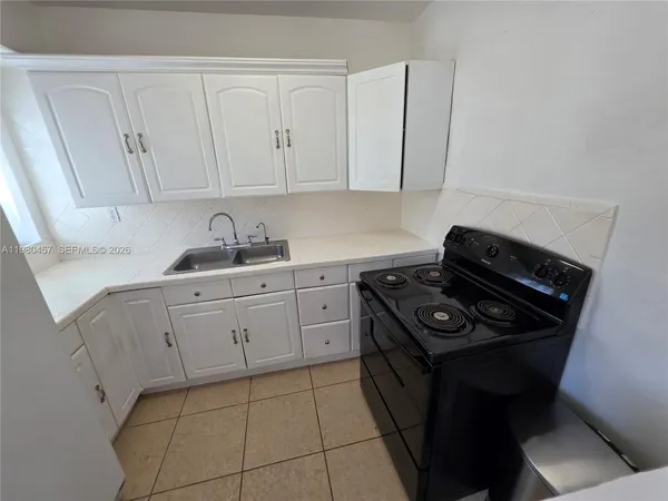 a kitchen with white cabinets and appliances