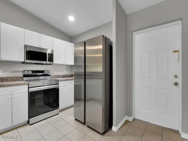 an empty room with chandelier fan and windows