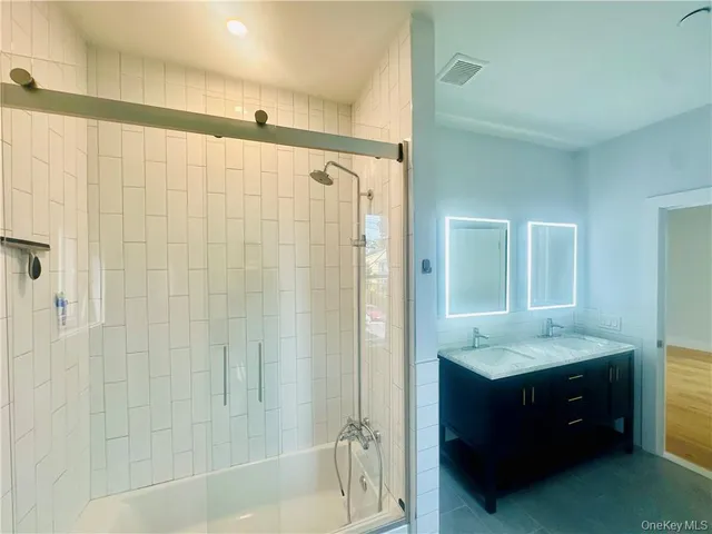a bathroom with a tub shower vanity and a sink