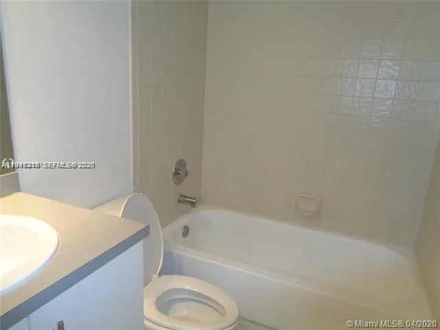a bathroom with a granite countertop sink and a bathtub