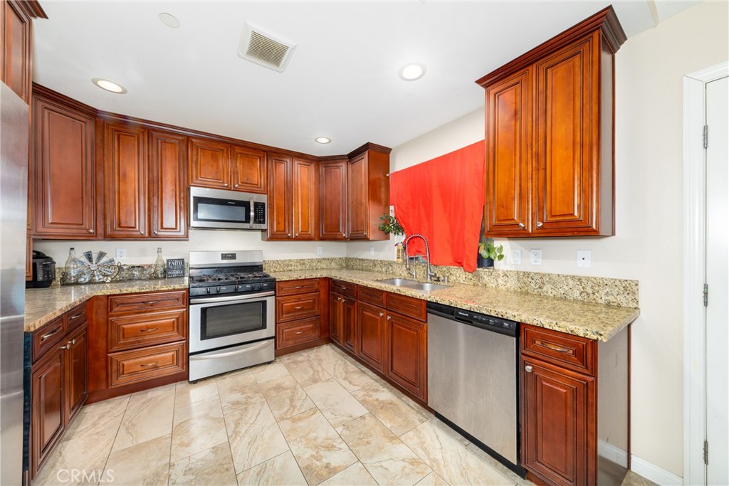 14632 Maricopa Road Victorville, CA 92392 - Photo 3 of 43 a kitchen with stainless steel appliances granite countertop wooden cabinets a stove top oven a sink and dishwasher