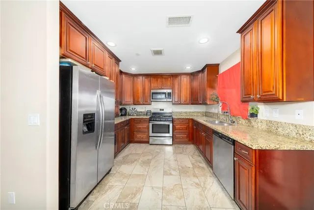 a large kitchen with stainless steel appliances granite countertop a stove a sink dishwasher a refrigerator and a microwave oven