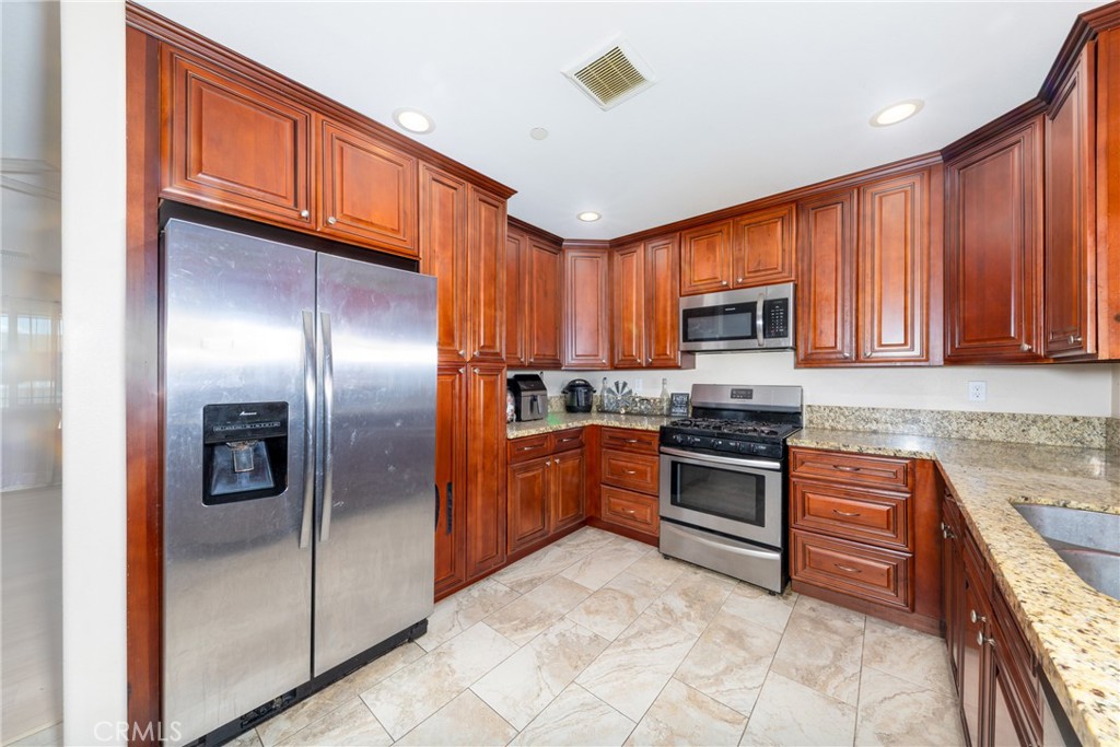 14632 Maricopa Road Victorville, CA 92392 - Photo 5 of 43 a kitchen with stainless steel appliances granite countertop a refrigerator a stove top oven a sink and dishwasher