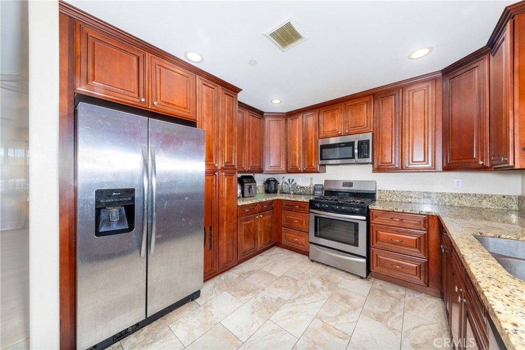14632 Maricopa Road Victorville, CA 92392 - Photo 5 of 43 a kitchen with stainless steel appliances granite countertop a refrigerator a stove top oven a sink and dishwasher