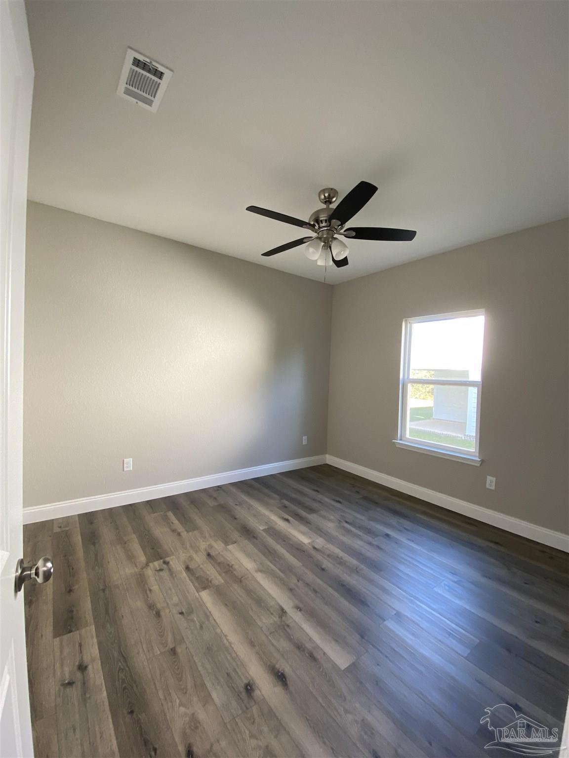 6768 Contentment Street Milton, FL 32583 - Photo 12 of 21 an empty room with wooden floor fan and windows