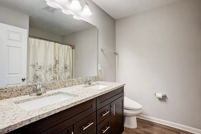 a bathroom with a granite countertop sink a toilet and a mirror