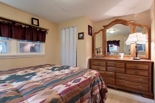 a bedroom with a bed and a large mirror on the dresser