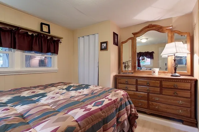 a bedroom with a bed and a large mirror on the dresser