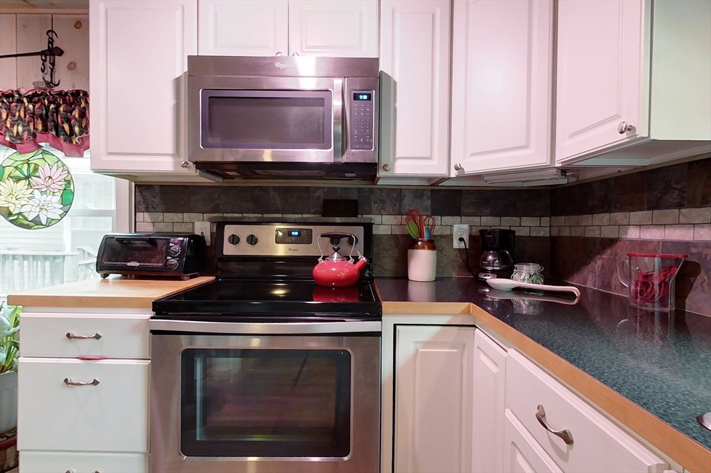 239 Ayer Road, Unit 16 Littleton, MA 01460 - Photo 4 of 22 a kitchen with stainless steel appliances granite countertop a stove a microwave and cabinets
