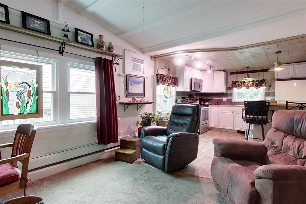 239 Ayer Road, Unit 16 Littleton, MA 01460 - Photo 6 of 22 a living room with furniture a flat screen tv and kitchen view