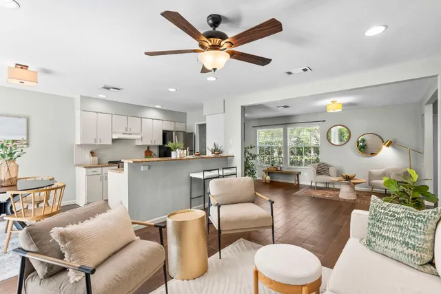 a living room with furniture kitchen view and a large window