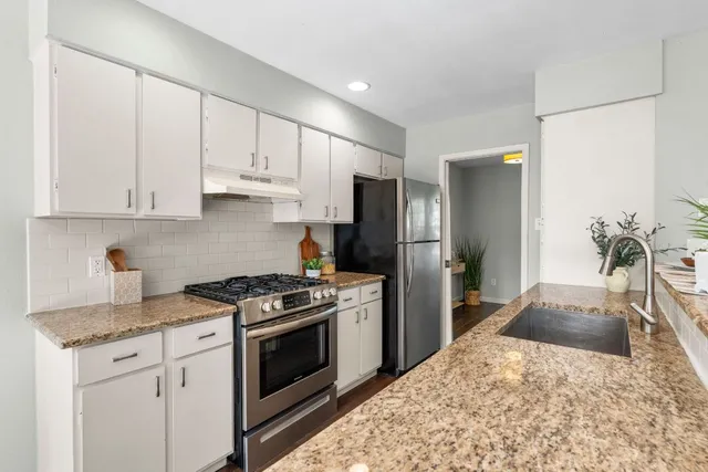a kitchen with stainless steel appliances granite countertop a stove a refrigerator and a sink