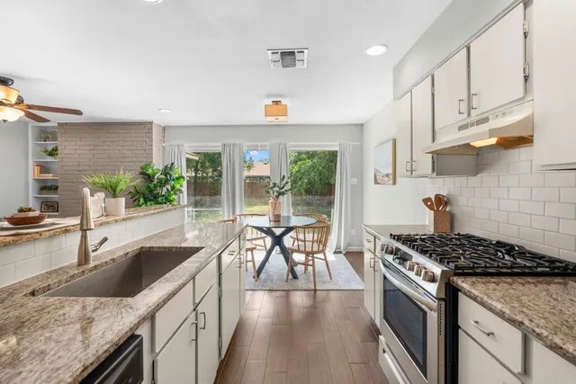 a kitchen with granite countertop a sink stove and cabinets
