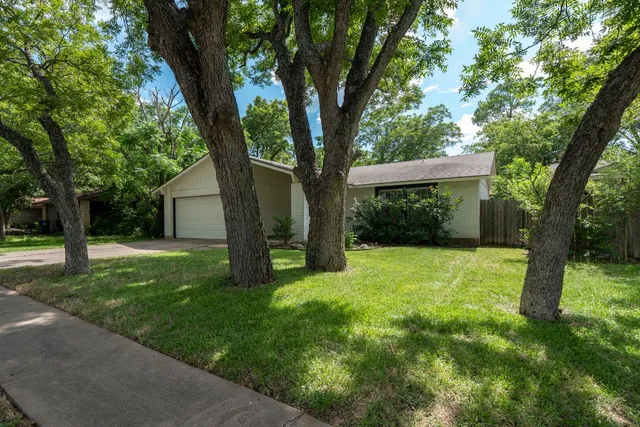 a view of a house with backyard and a tree