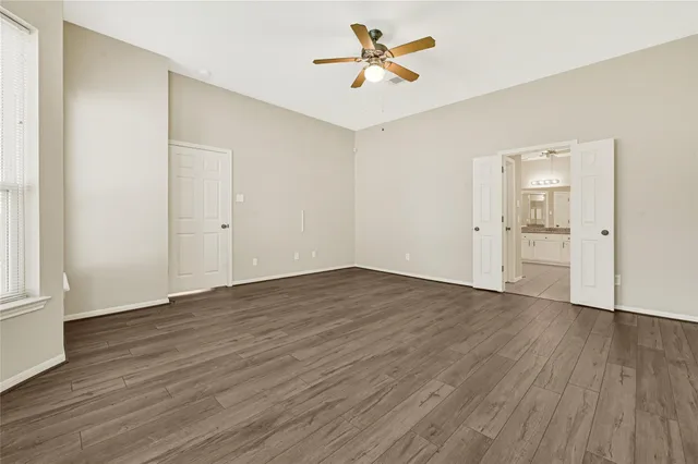 an empty room with wooden floor and ceiling fan