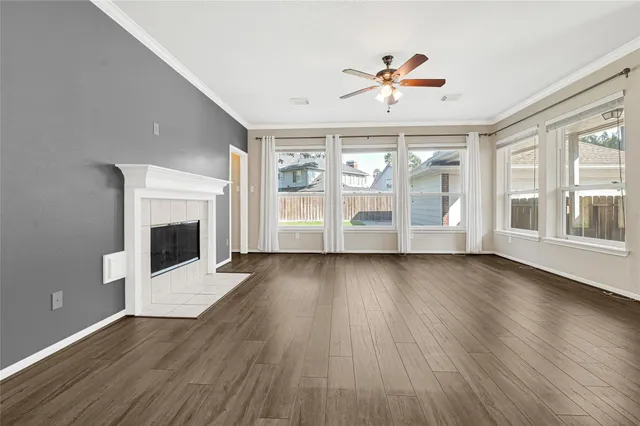 an empty room with wooden floor fireplace and windows