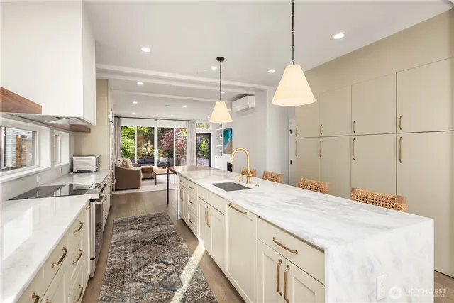 a large kitchen with kitchen island a stove a sink a dining table and chairs with wooden floor