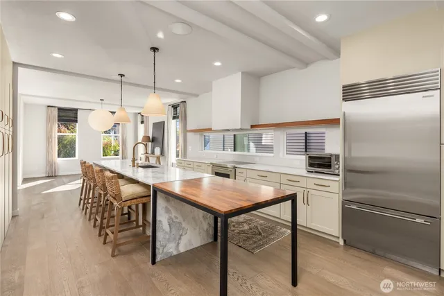 a kitchen with stainless steel appliances granite countertop a kitchen island a stove a refrigerator a oven a sink with a dining table and chairs