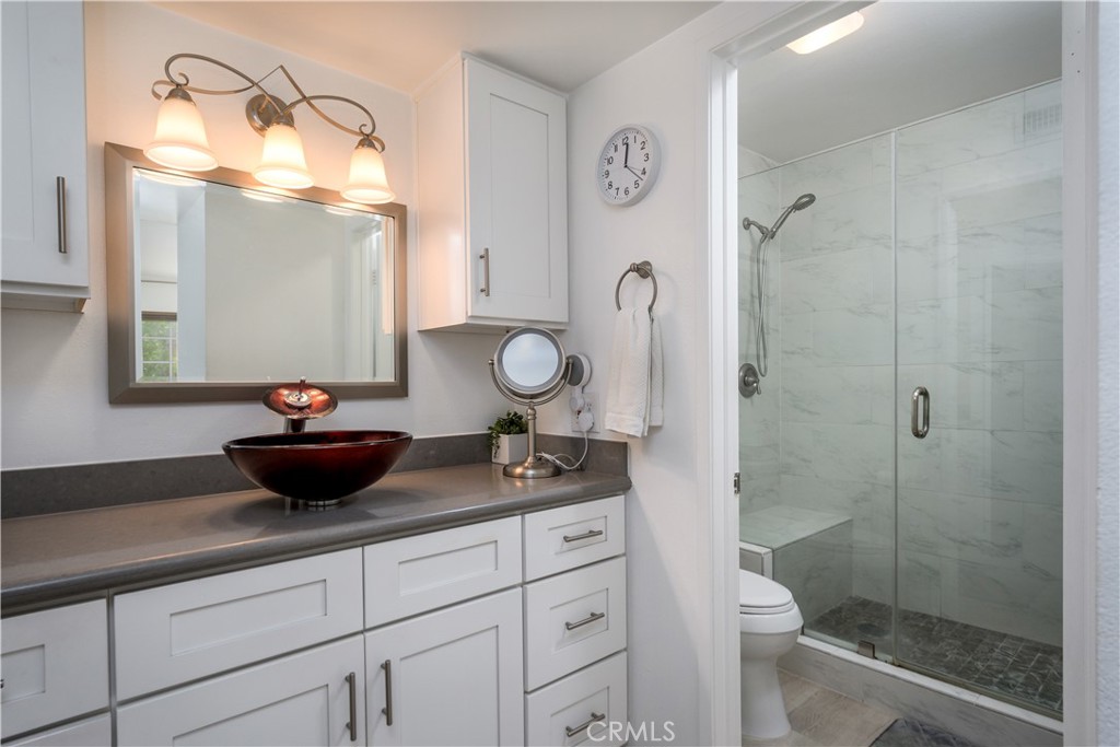 628 Daisy Avenue, Unit 222 Long Beach, CA 90802 - Photo 13 of 25 a bathroom with a granite countertop sink a toilet a mirror and shower
