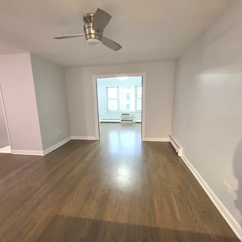 a view of empty room with wooden floor and fan