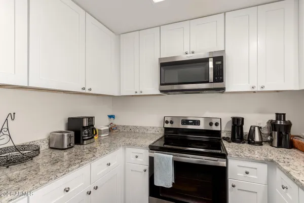 a kitchen with granite countertop white cabinets and a stove top oven with granite countertops