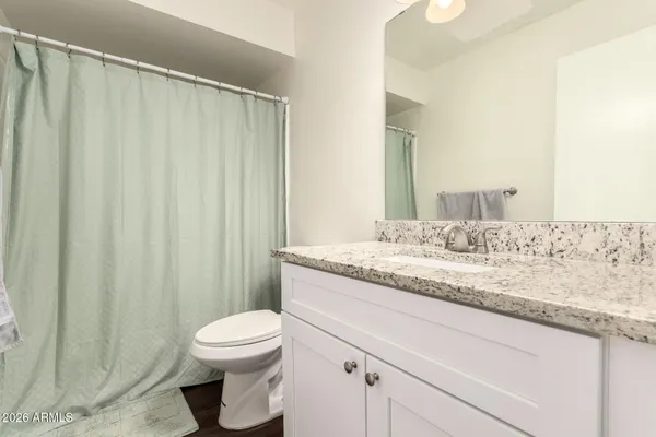 a bathroom with a granite countertop sink toilet and a mirror